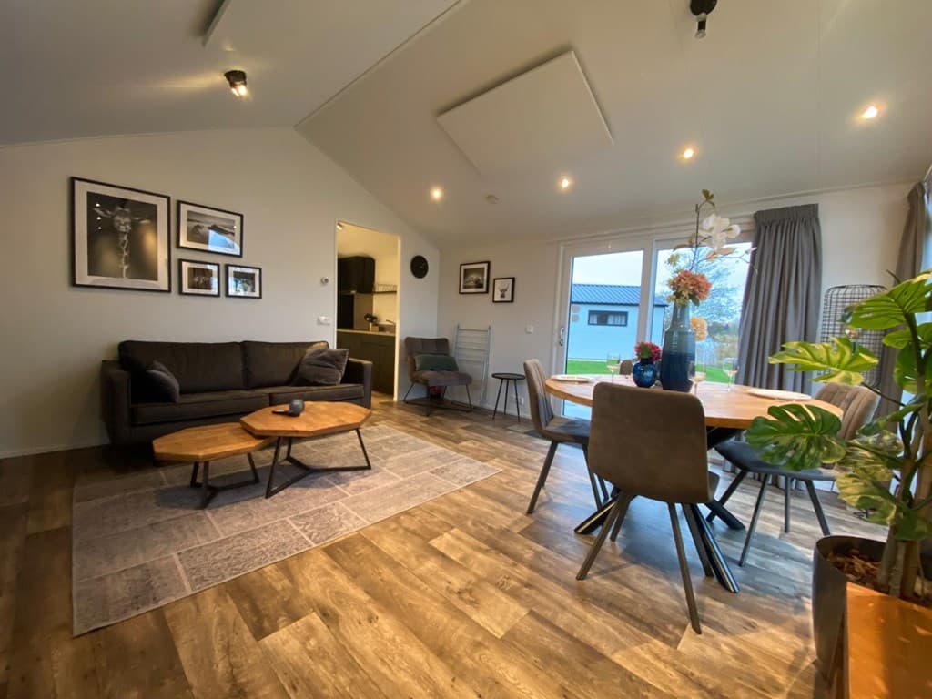 Ruime woonkamer met een bank, eettafel en toegang tot buiten met grote ramen en moderne inrichting