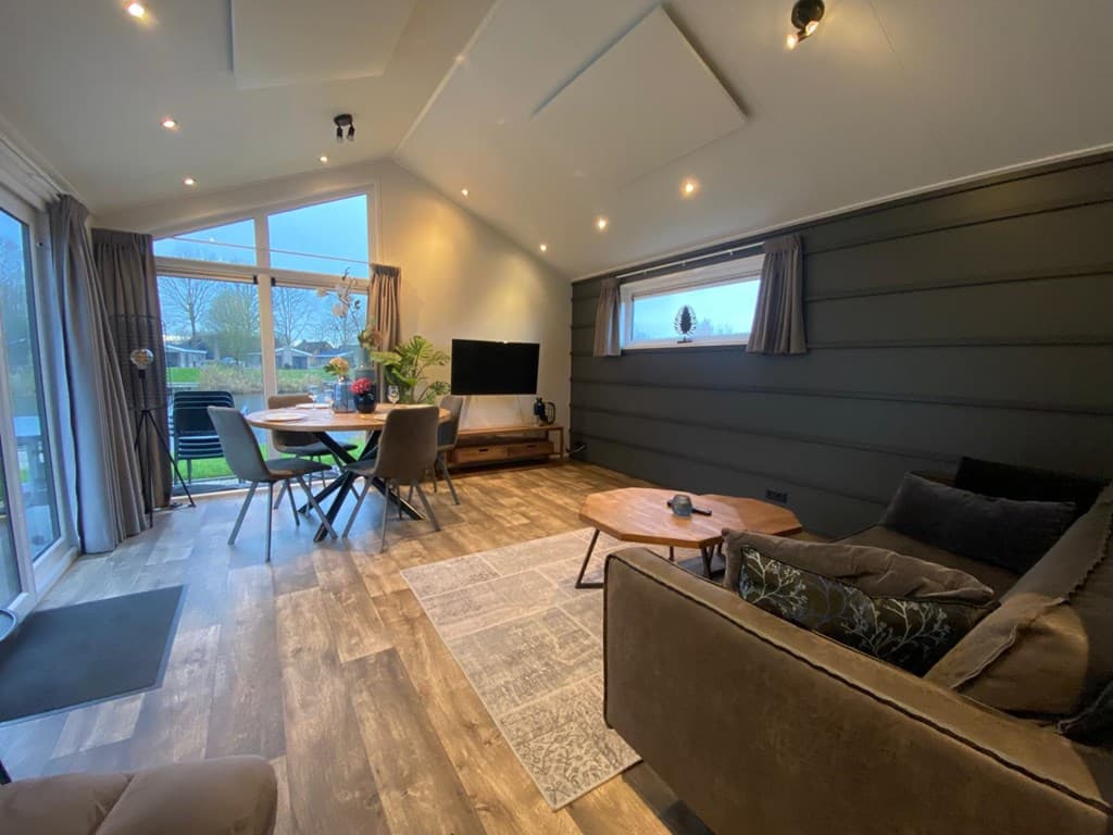 Moderne woonkamer met een zithoek, eetgedeelte en grote ramen met uitzicht op de tuin.