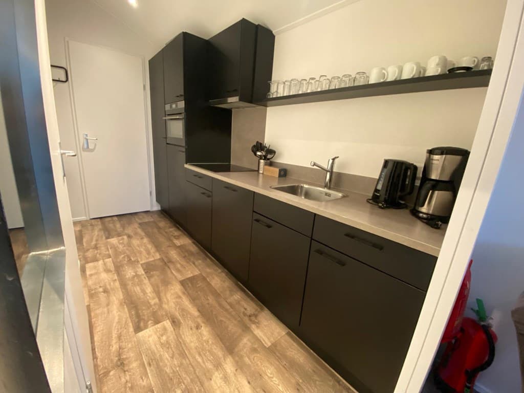 Moderne keuken met zwarte kasten, aanrecht, een spoelbak en keukentoestellen zichtbaar.