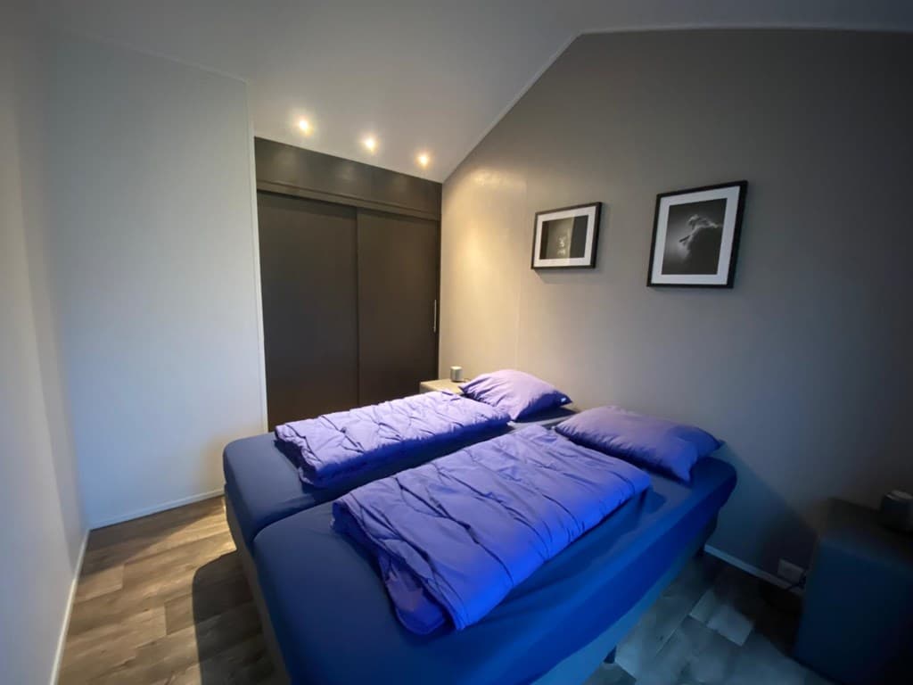 Slaapkamer met twee eenpersoonsbedden, houten vloer en ingemaakte kast, enkele foto’s aan de muur