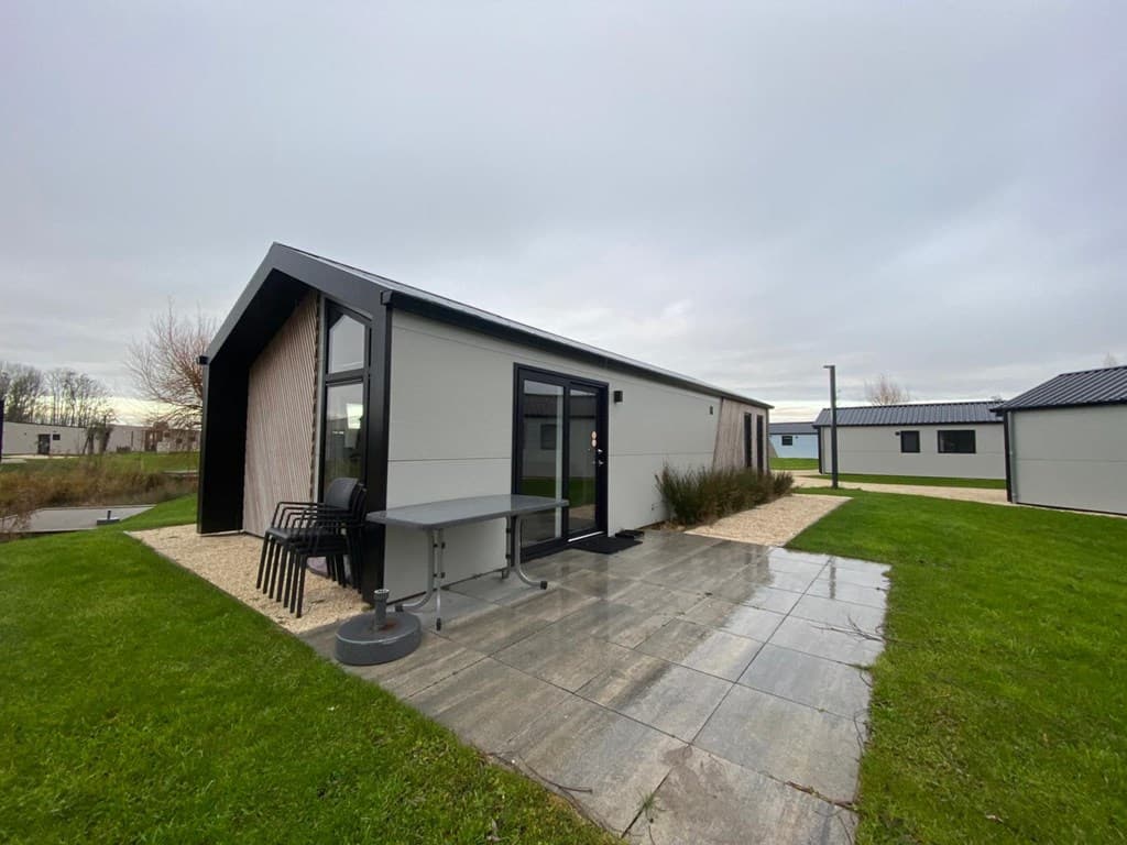 Moderne vakantiewoning met glazen deur, een kleine tuin en betegeld terras met tuinmeubilair