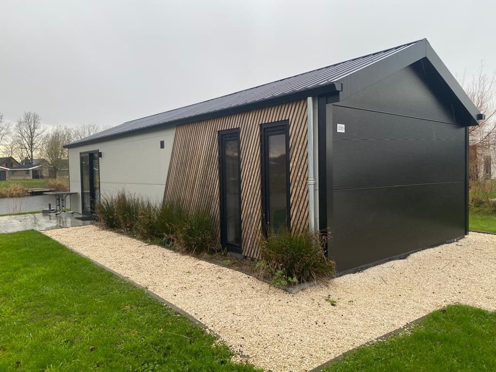 Moderne vakantiewoning met een combinatie van donkere en lichte gevel en plantenbedden rondom het terrein.