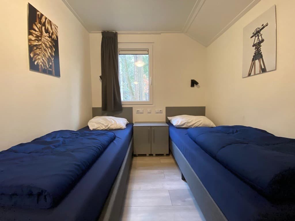 Slaapkamer met twee eenpersoonsbedden, ramen met uitzicht op buiten en een neutrale kleurenpalet.