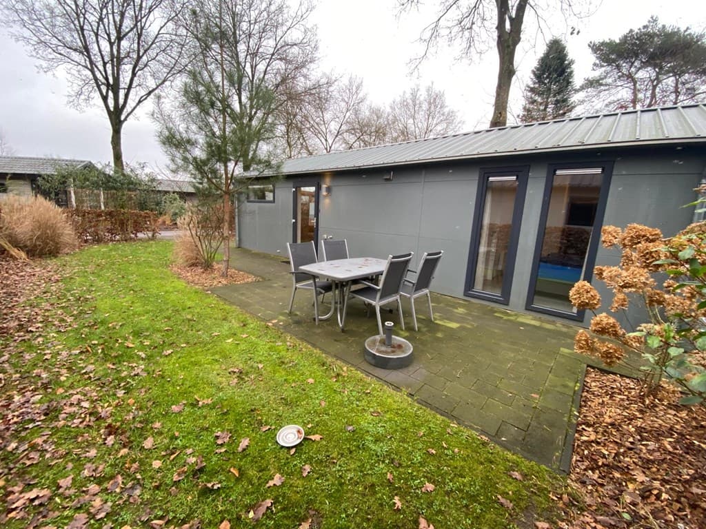 Moderne vakantiewoning met terras en zitgedeelte, omgeven door groen en bomen