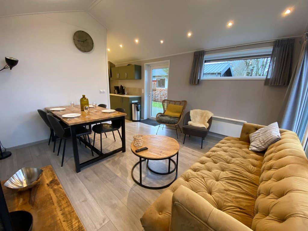 Hedendaagse woonkamer met eettafel, bank, fauteuil en veel natuurlijk licht vanuit grote ramen