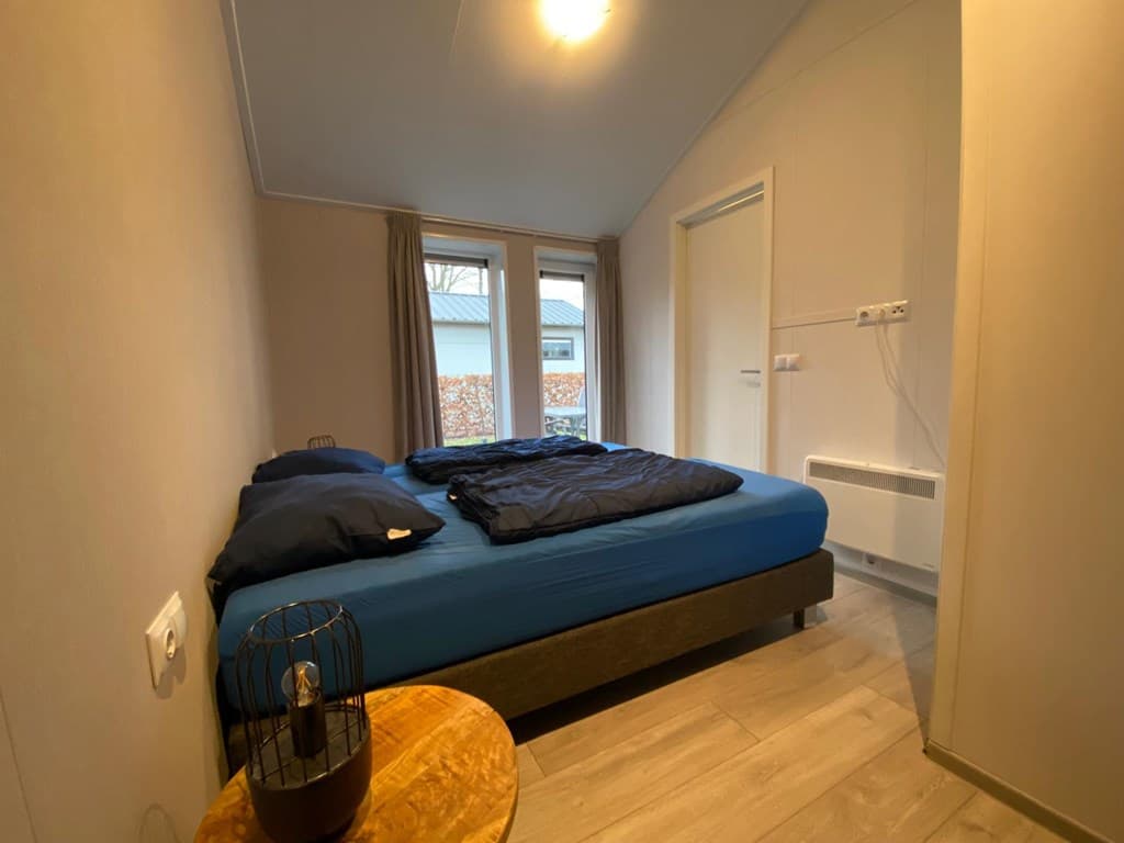 Slaapkamer met een tweepersoonsbed, nachttafel en grote raampartij naar buiten