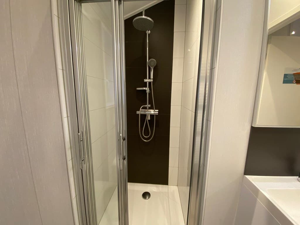 Inloopdouche met glazen wanden en moderne regendouche in een lichte badkamer