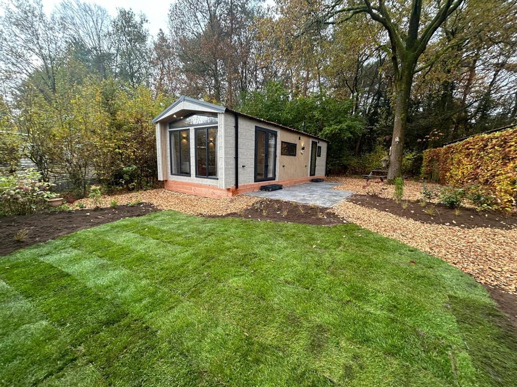 Moderne vakantiewoning met tuin en grindpad, omringd door bomen en struiken in Veluwepark de Bosgraaf.
