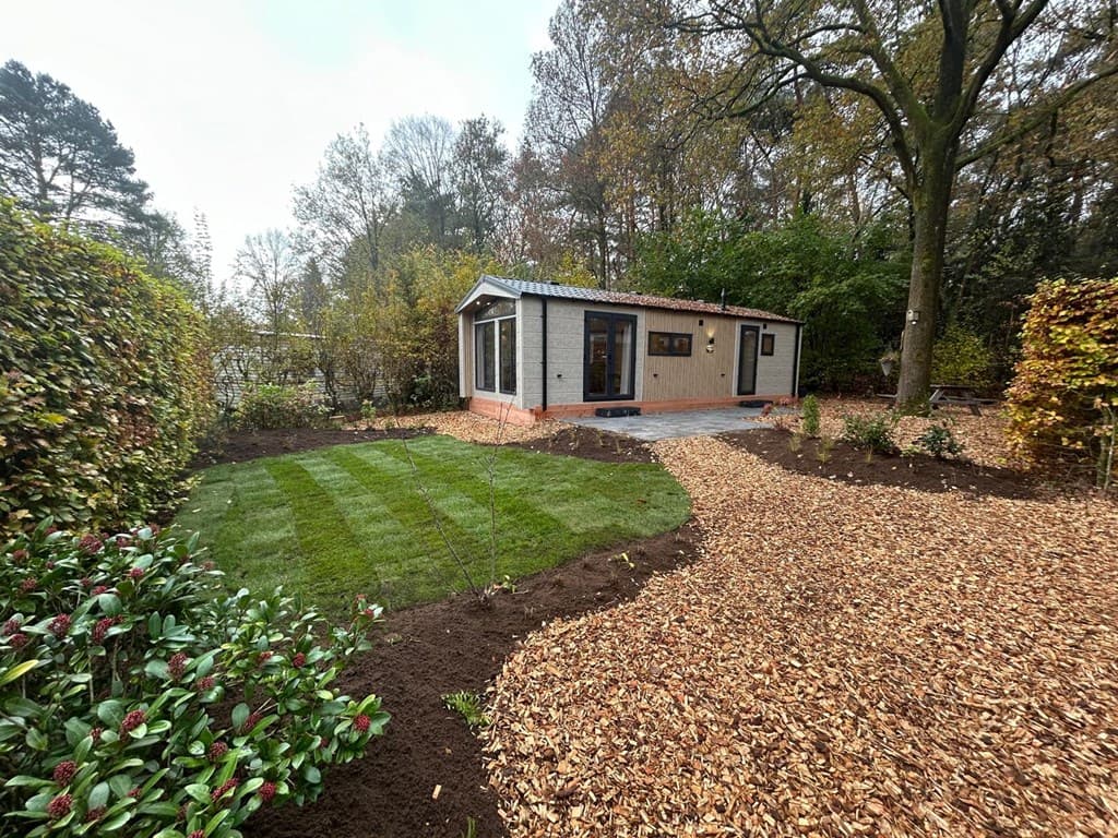 Moderne vakantiewoning met een aangelegde tuin en bestrating, omgeven door bomen en groen op Veluwepark de Bosgraaf.