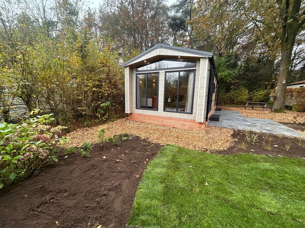 Moderne vakantiewoning met grote ramen, omliggend door groen en herfstachtige bomen op Veluwepark de Bosgraaf