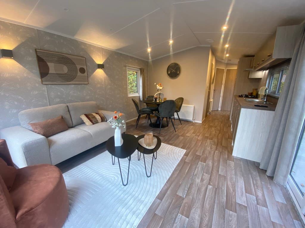Woonkamer met bank, eettafel en keuken in lichte kleuren en moderne inrichting