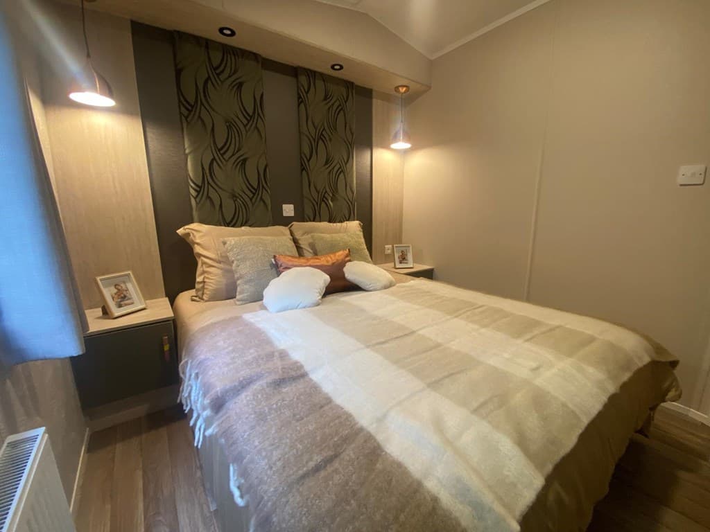 Slaapkamer met een tweepersoonsbed, wanddecoratie en sfeerverlichting aan beide kanten van het bed.
