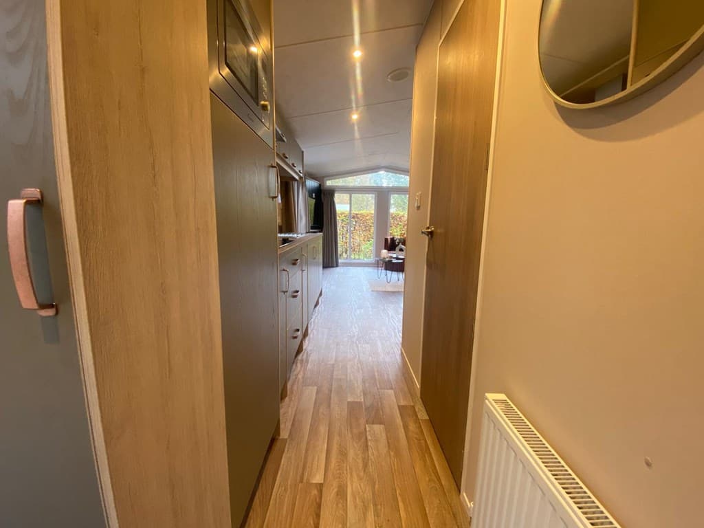 Ingang naar de woning met een zicht op de woonkamer en een grote glazen deur naar buiten.