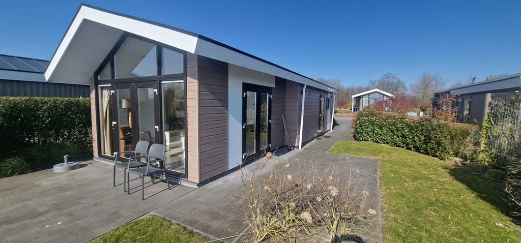 Moderne vakantiewoning met grote ramen, terras, zitplaatsen en een groene tuin bij EuroParcs Markermeer.