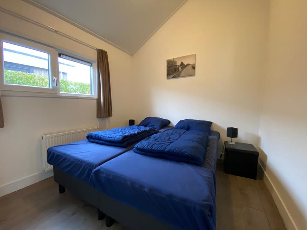Slaapkamer met twee enkele bedden, een raam en een schilderij aan de muur