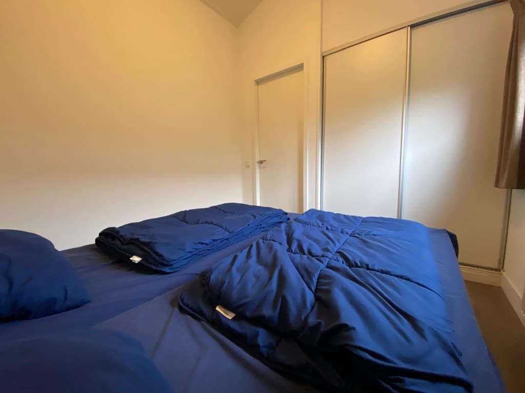 Slaapkamer met twee stapels van blauwe dekbedden en een kast met spiegeldeuren.