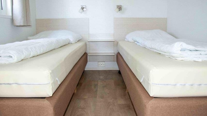 Slaapkamer met twee eenpersoonsbedden, nachtkastje en wandlampen aan de wanden.