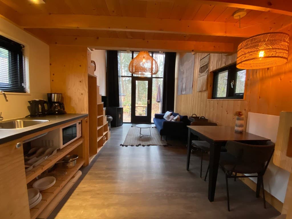 Gezellige open keuken met houten elementen, een eetkamer, en een woonkamer met uitzicht op de natuur
