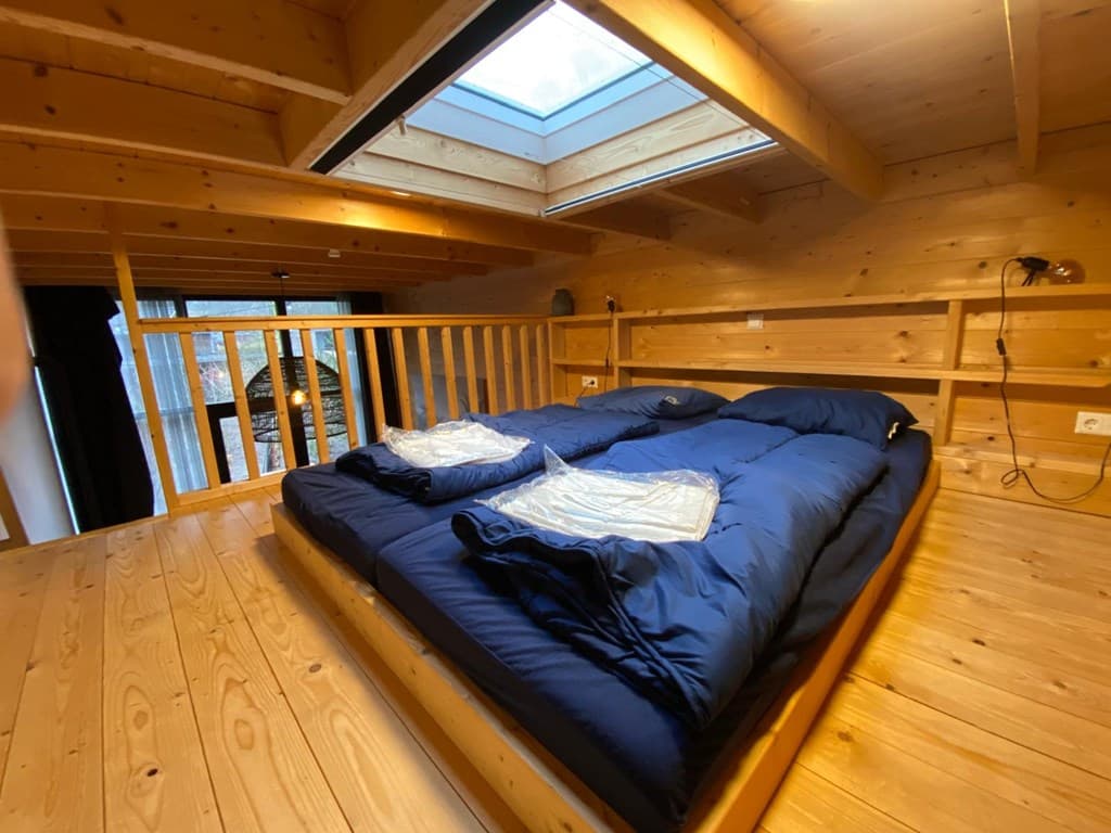 Houten slaapkamer met een tweepersoonsbed en een dakraam voor natuurlijk licht