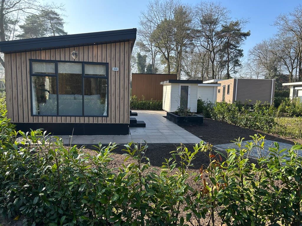Moderne vakantiewoning met houten gevel, terras en omliggende groene tuin op Camping De Konijnenberg in Harderwijk