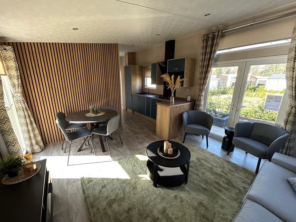 Gezellige woonkamer met eetgedeelte, moderne keuken en grote ramen met uitzicht op de tuin.