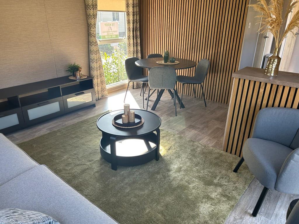 Modern interieur met zitgedeelte, eettafel en stoelen, houten accenten en planten bij Camping De Konijnenberg in Harderwijk