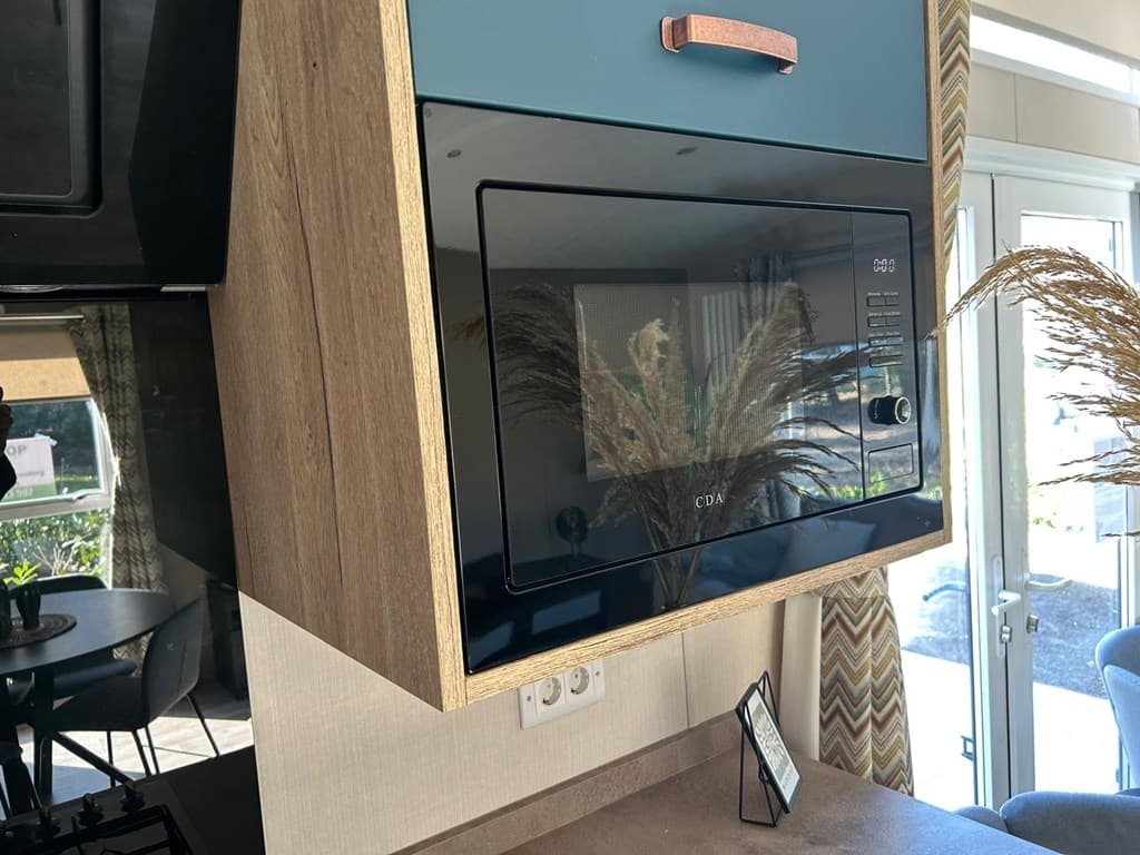 Moderne keuken met een ingebouwde microwave in een houten kast en een grijze werkblad, natuurlijke decoratie zichtbaar