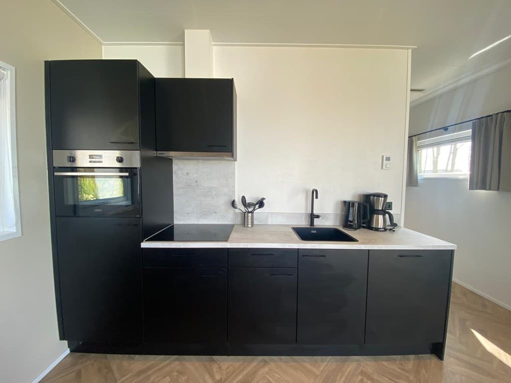 Moderne keuken in zwarte stijl met inbouwapparatuur en een aanrecht met spoelbak, in een lichte ruimte