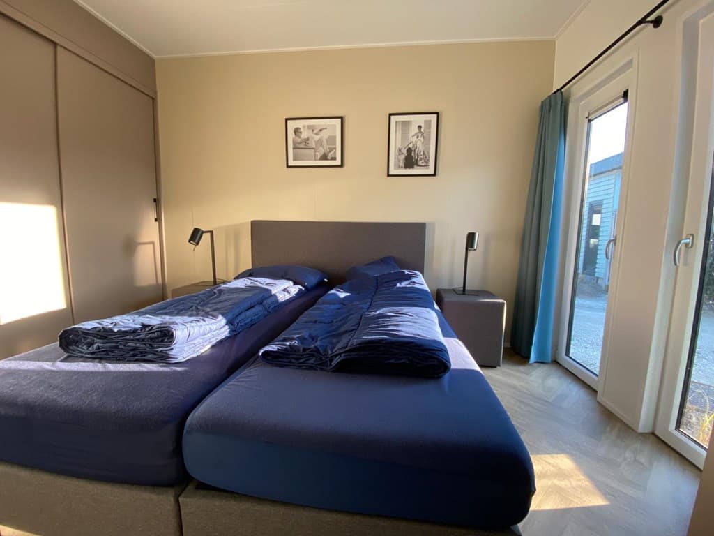 Slaapkamer met twee aparte bedden, nachtkastjes, lampen en raam met uitzicht op buiten.