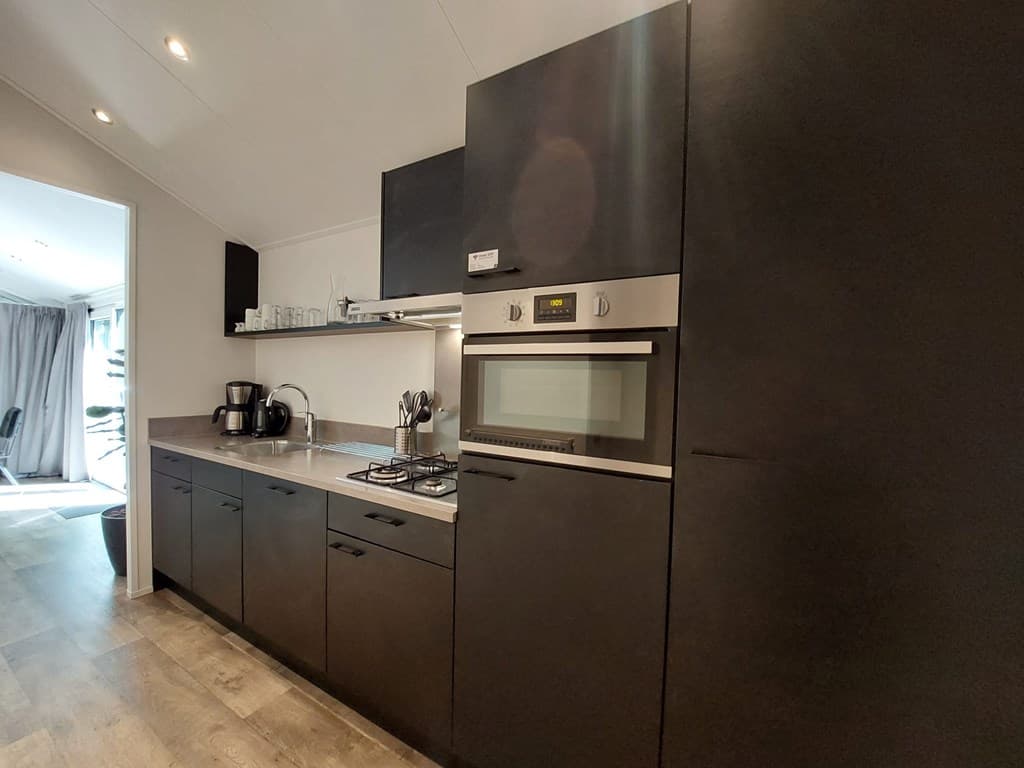 Moderne keuken met zwarte keukenkasten, oven, kookplaat en keukenapparatuur zichtbaar.