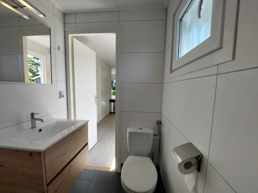 Moderne badkamer met een wastafel, toilet en toegang tot een andere kamer.