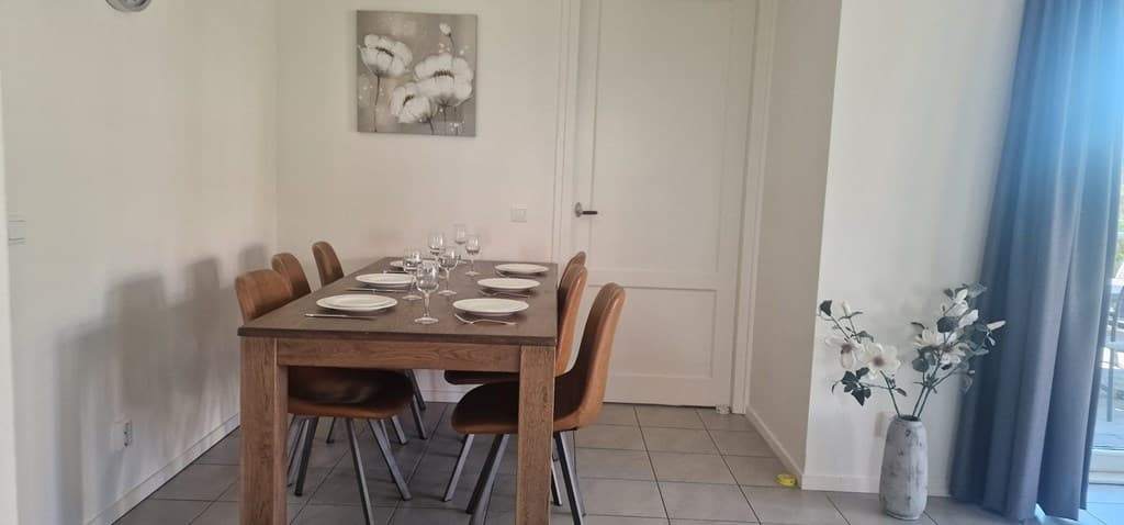 Eettafel met stoelen, gedekte tafel en decoratieve bloempot in lichte, moderne ruimte