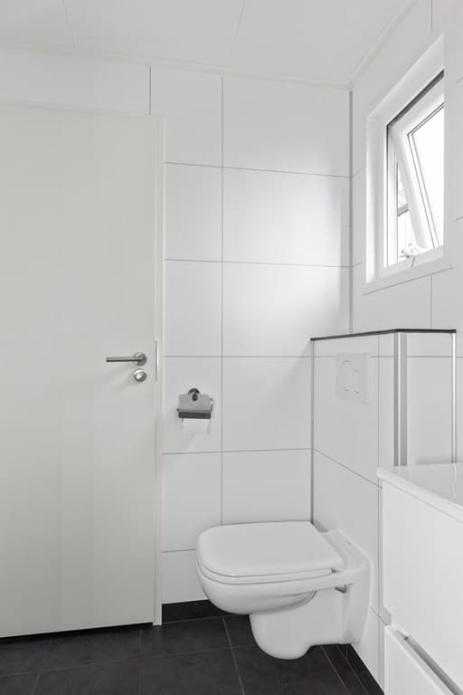 Witte badkamer met toilet, wastafelmeubel en raam voor natuurlijk licht