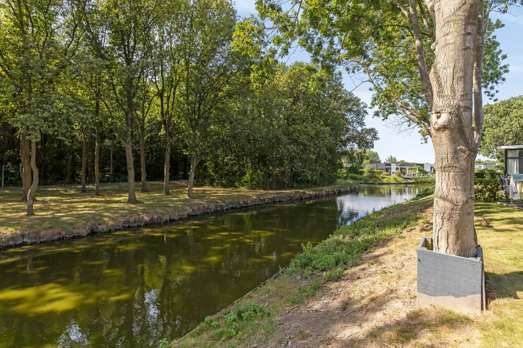 Zicht op een kanaal omgeven door bomen en groene ruimte bij EuroParcs Spaarnwoude, Halfweg.