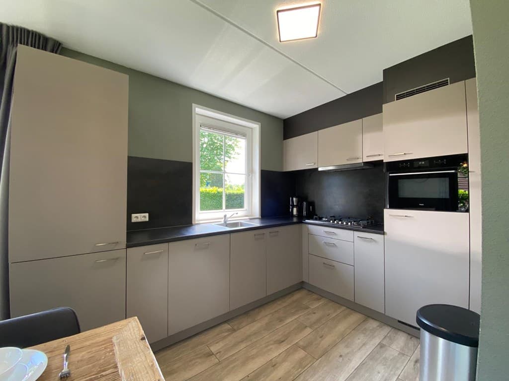 Moderne keuken met kookplaat, oven, koelkast en venster met uitzicht op de tuin