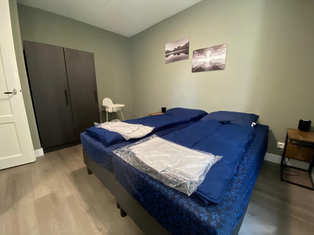 Slaapkamer met twee aparte bedden, een kledingkast en wanddecoratie aan de muur.