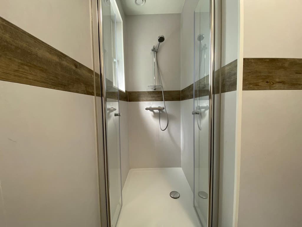 Moderne inloopdouche met glazen wanden en houten accentlijnen in een lichte badkamer