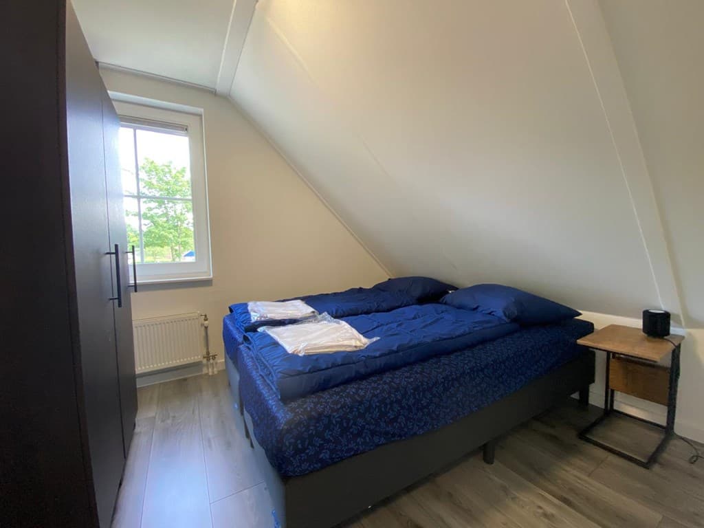 Sfeervolle slaapkamer met twee bedden, een kledingkast en een raam met uitzicht op de groene buitenomgeving