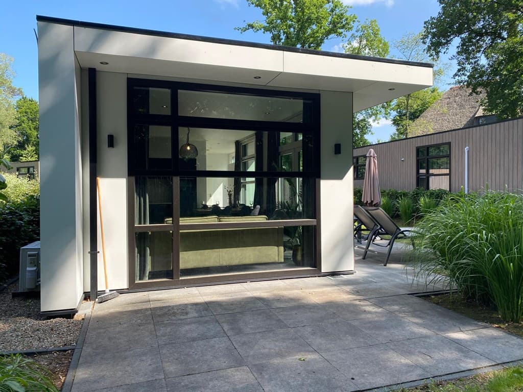Moderne vakantiewoning met grote ramen en een terras, omringd door groen en afstand tot andere woningen.