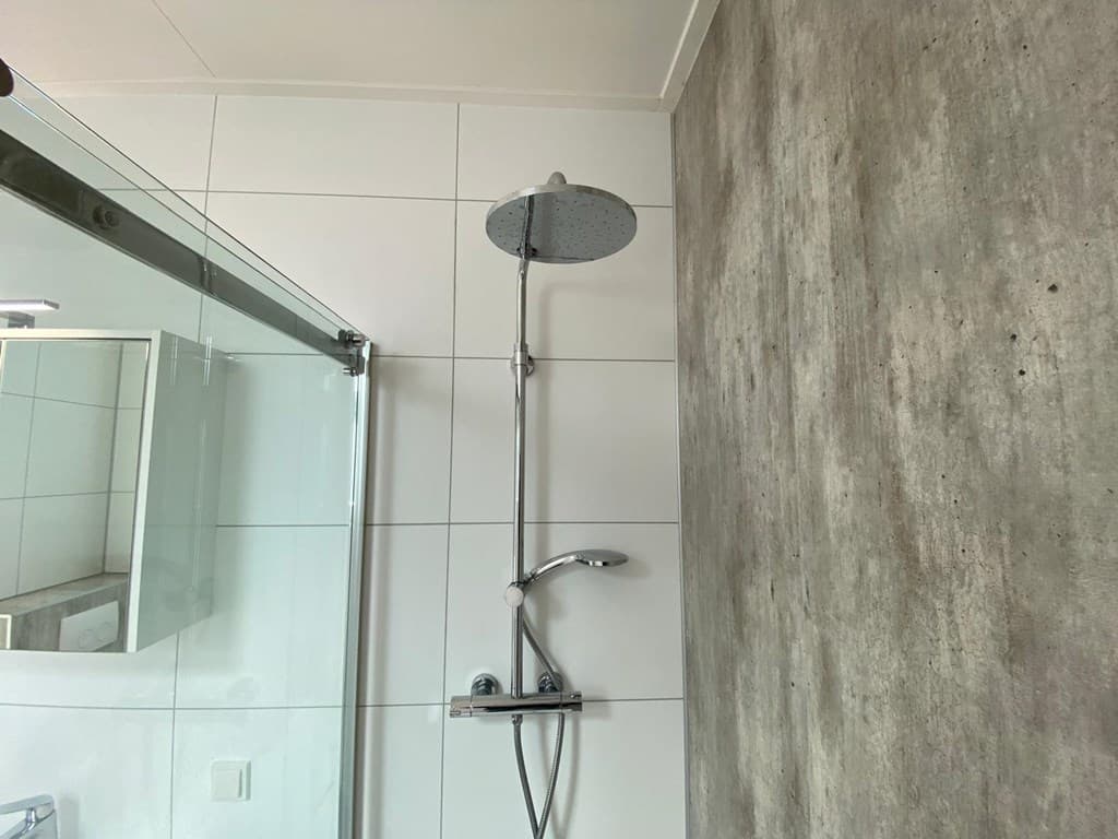 Douchewand met regendouche en betegelde wand in een moderne badkamer