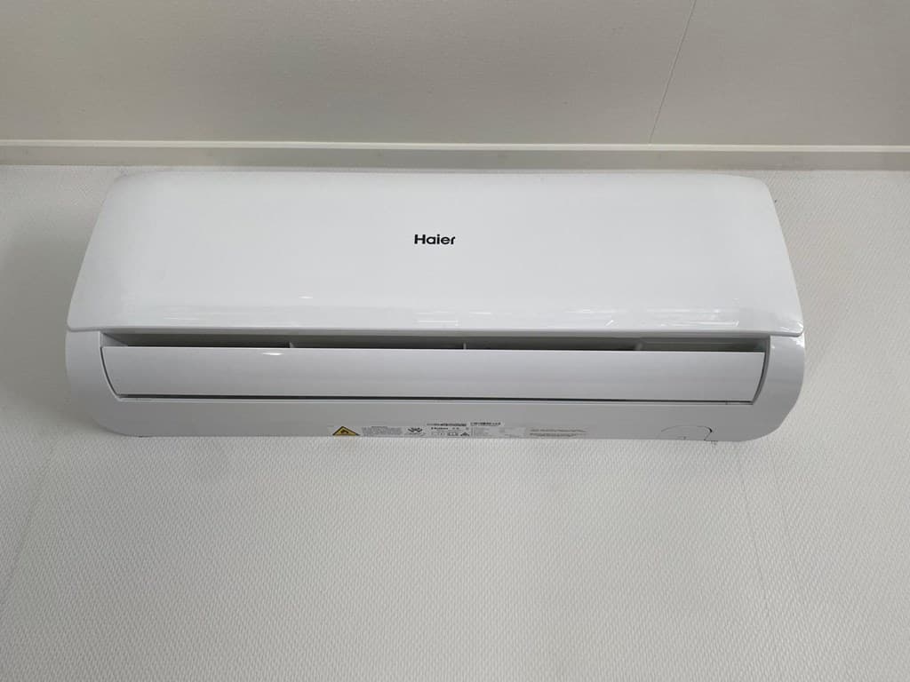 Airconditioningseenheid aan de muur in een interieur met heldere wanden en een lichtkleurige vloer.