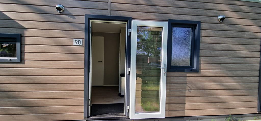 Moderne woning met houten gevel en dubbele deur aan de voorkant, nummer 90 zichtbaar naast de deur.