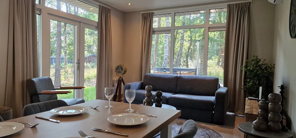 Hoekwoonkamer met bank, glazen deuren naar de tuin en een eetgedeelte met tafel en stoelen.