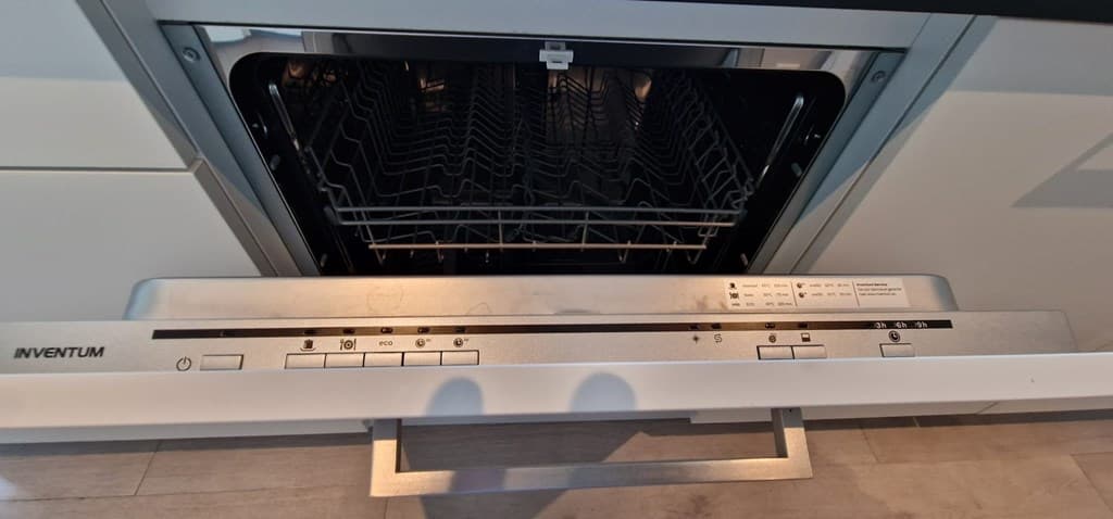 Afbeelding van een open vaatwasser met een gedeeltelijk zichtbare lade en bedieningspaneel in een moderne keuken.