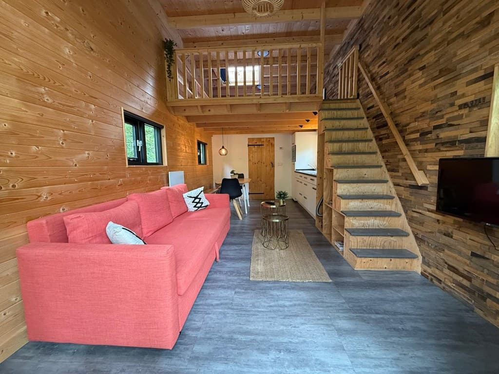 Houten vakantiewoning met een ruime zithoek, trap naar boven en moderne inrichting met open keuken en lichte kleuren