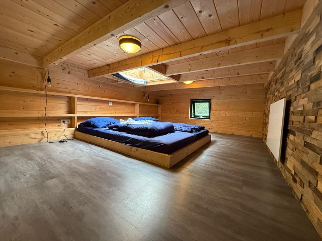 Slaapkamer met houten wanden, een groot tweepersoonsbed en een dakraam voor natuurlijk licht