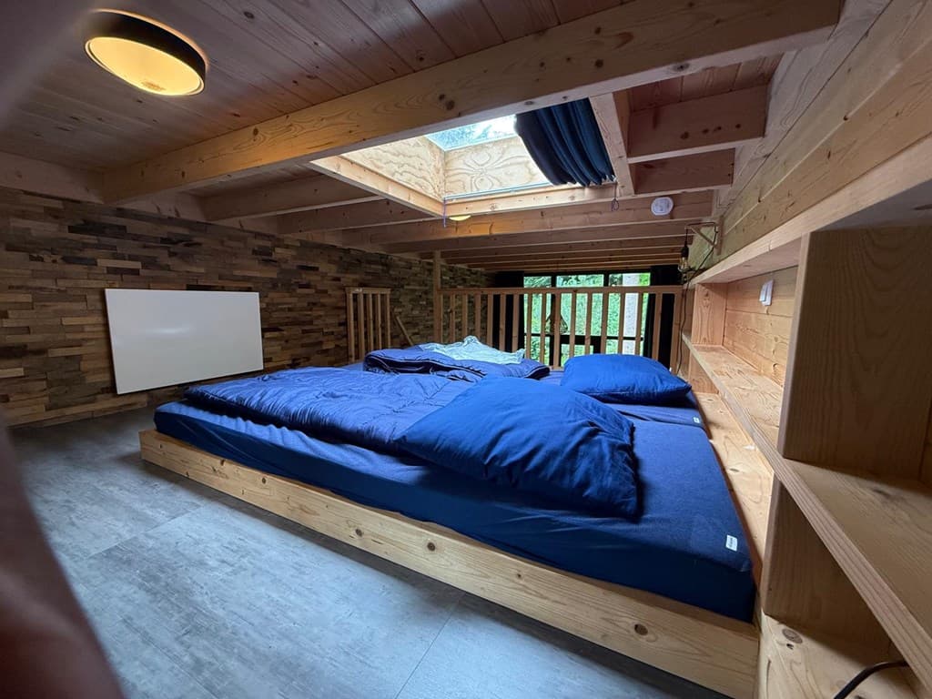 Sfeervolle slaapkamer met houten wanden, een lichtsysteem en een groot dakraam voor natuurlijk licht
