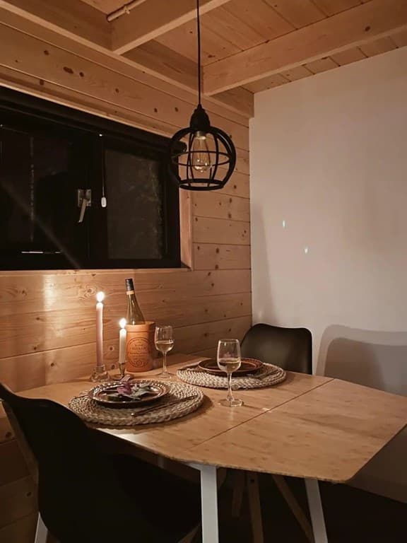 Eetkamer met houten wanden, een ronde tafel, glazen aan tafel en een hanglamp boven de tafel