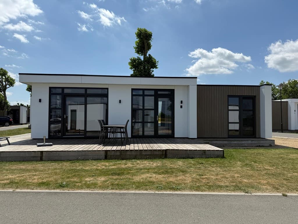 Moderne vakantiewoning met ruime houten terras en grote ramen, gelegen op een grasveld bij MarinaPark Bad Nederrijn.