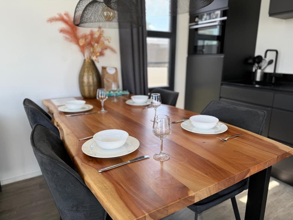Eettafel met stijlvolle borden, glazen en een vaas met decoratie in een moderne keukenomgeving.
